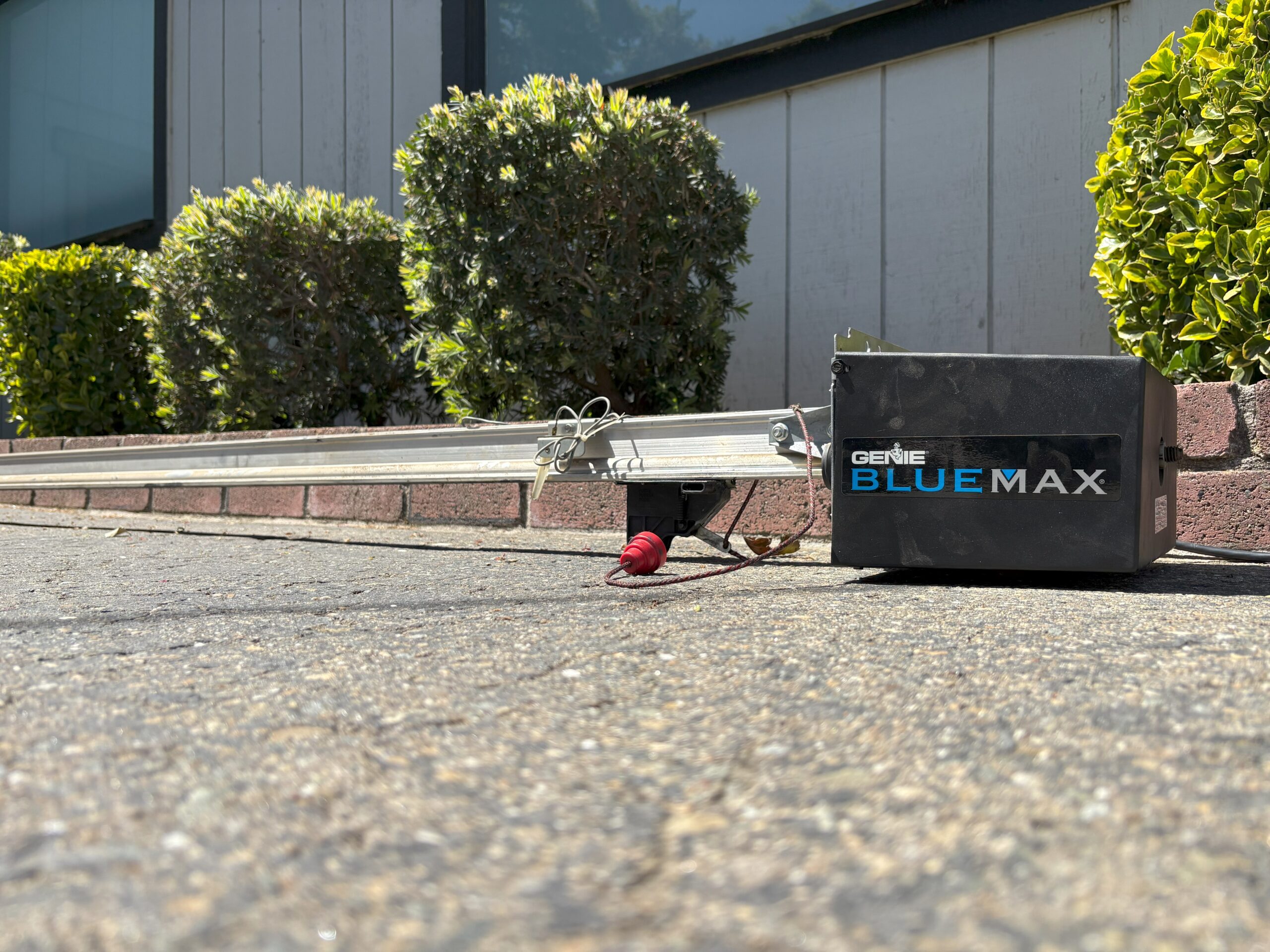A close-up of a Genie BlueMax garage door opener on a concrete surface, related to garage opener repair.