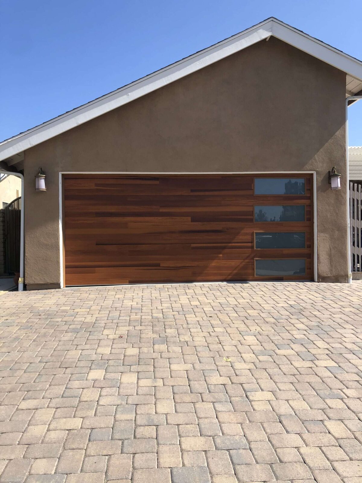 A modern home with a large wooden garage door featuring glass panels
